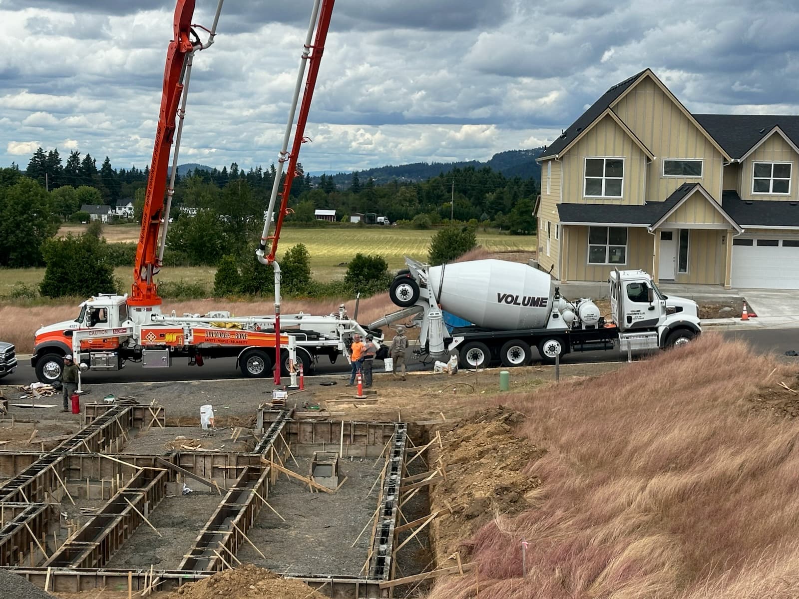 White VOLUME barrel mixer feeding a boom pump on a residential foundation pour