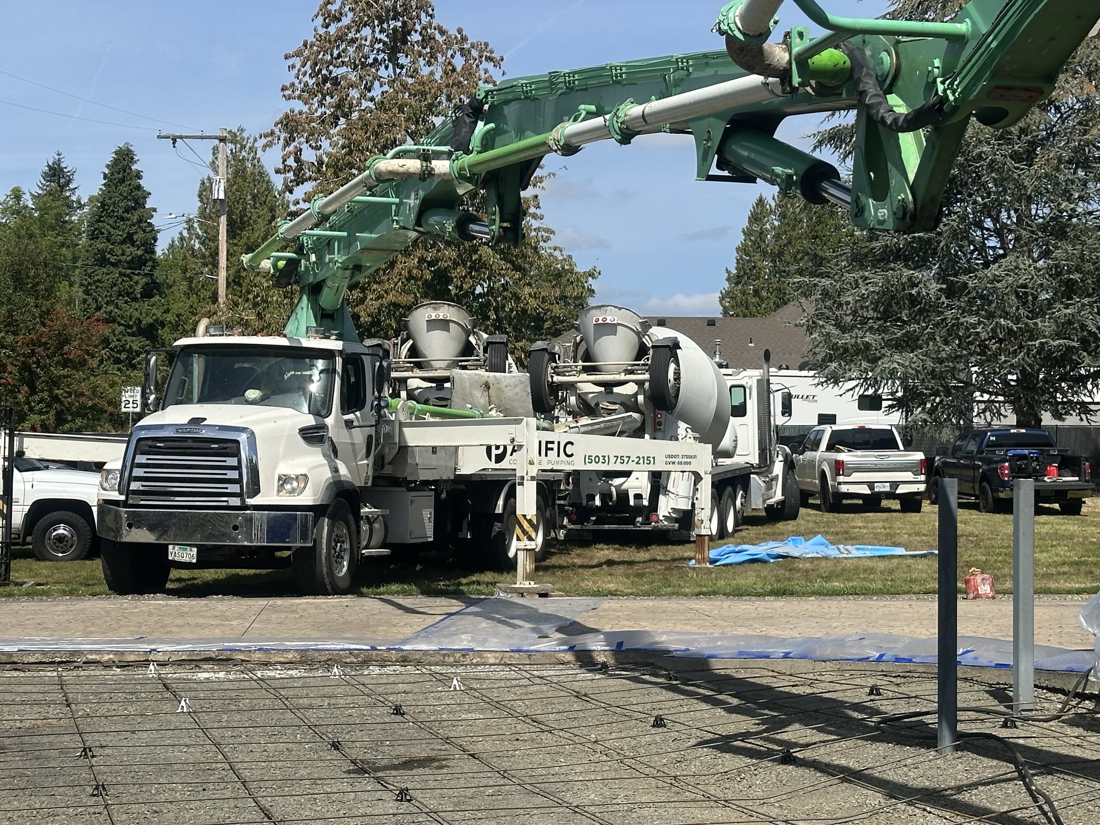 Boom pump and barrel mixer on a Gresham jobsite, green boom over a rebar pad